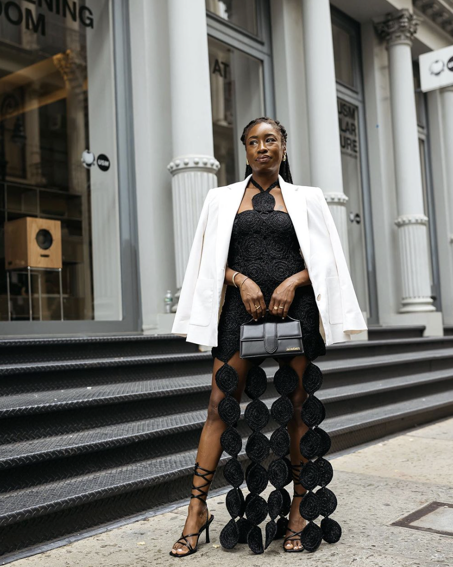 A woman in a black dress and white blazer.