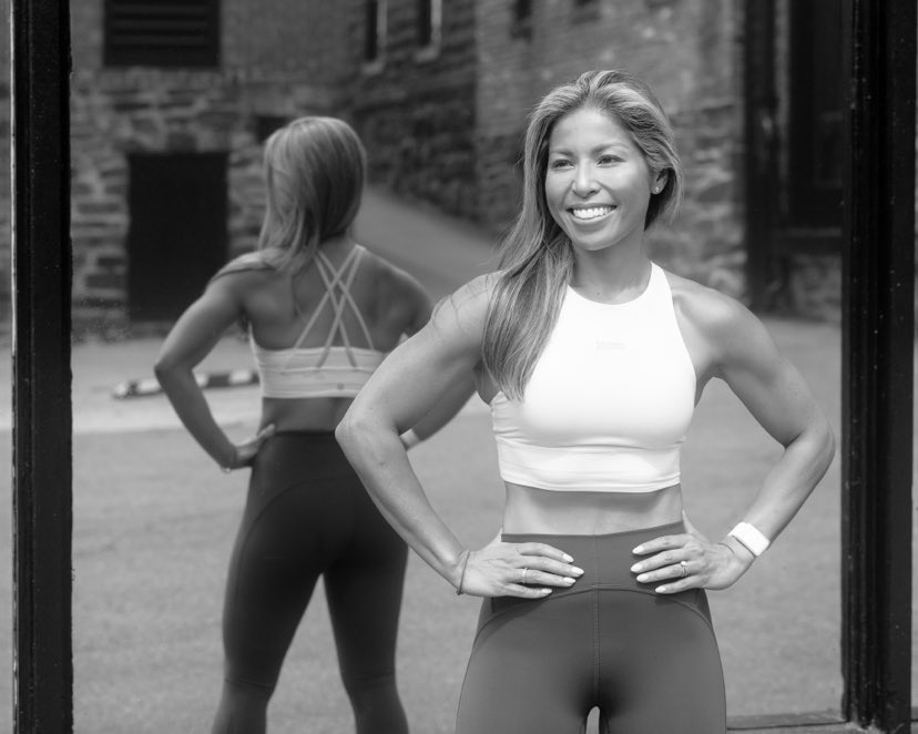 A woman smiling, wearing workout clothes