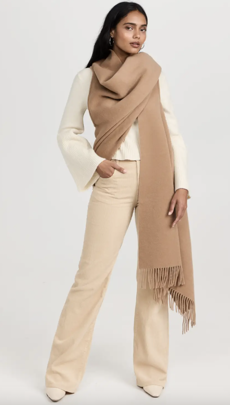 A woman wearing a white suit and a brown scarf