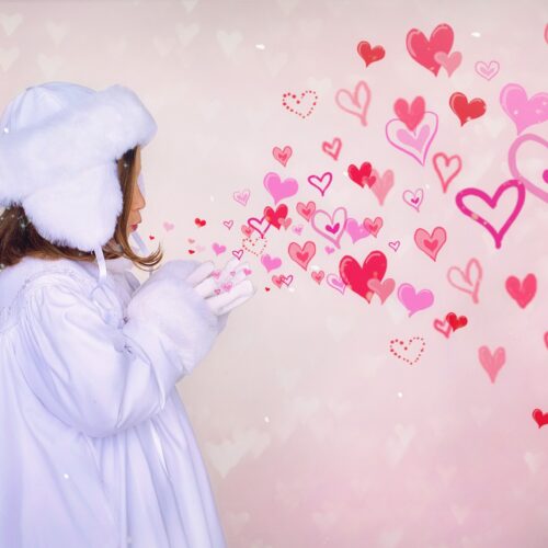 little girl appearing to blow hearts