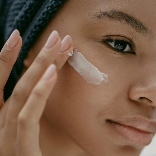 A woman applying lotion to her cheekbone