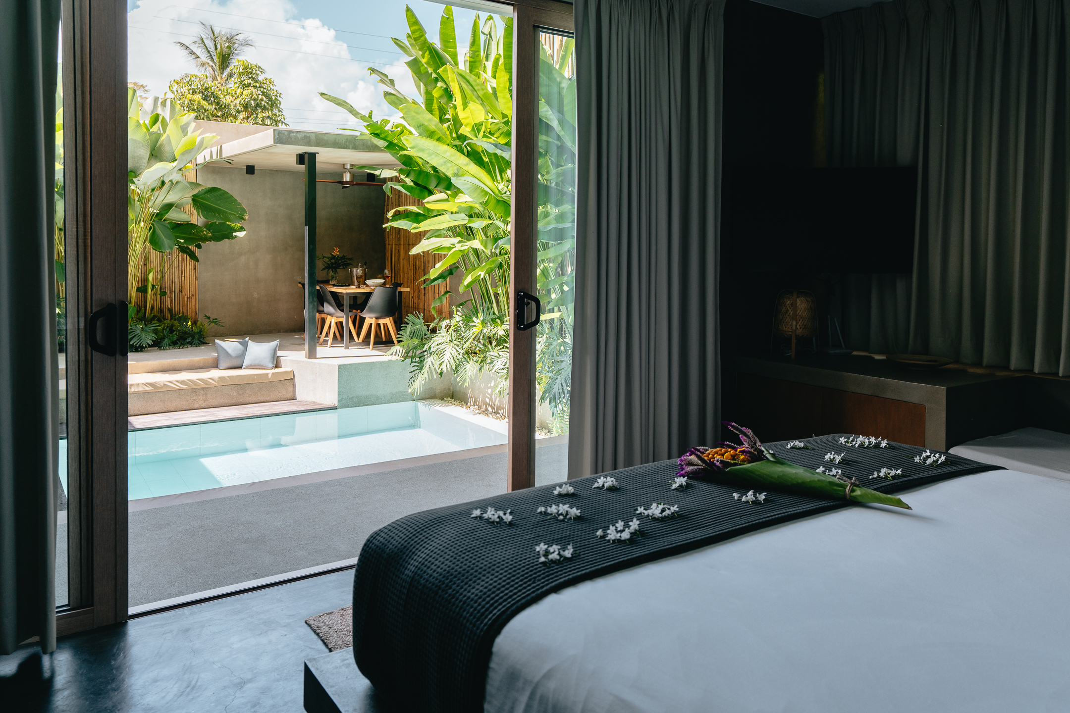 A hotel room with a view of a private pool and dining area