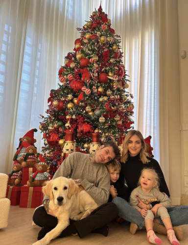 A family and their dog sitting by a Christmas tree