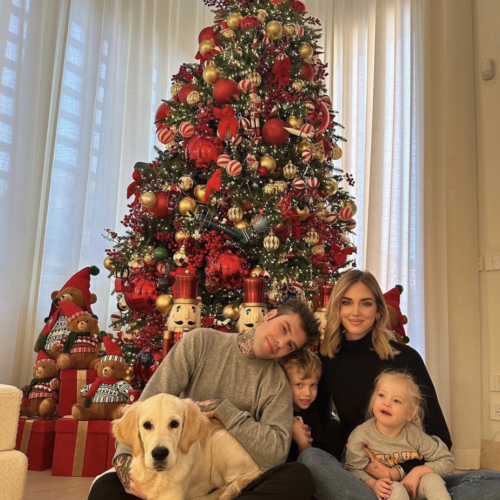 A family and their dog sitting by a Christmas tree