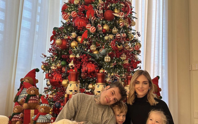 A family and their dog sitting by a Christmas tree